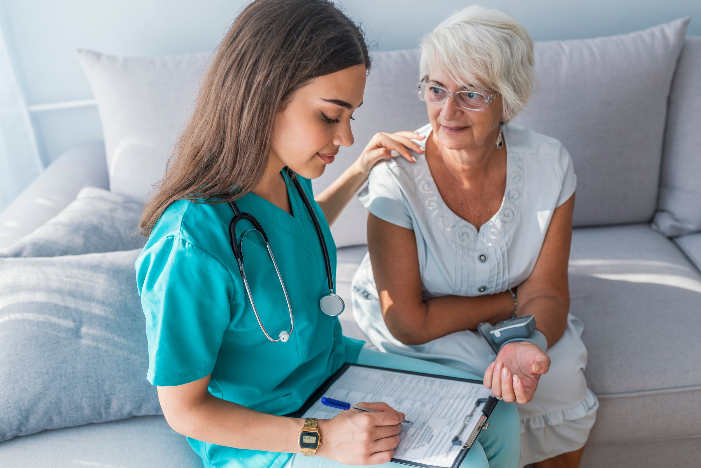 Nurse measuring blood pressure of senior woman at home